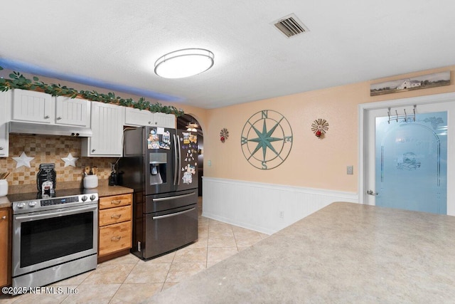 kitchen featuring stainless steel range with electric cooktop, black fridge, white cabinetry, tasteful backsplash, and light tile patterned floors