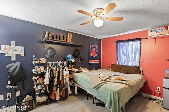 bedroom with ceiling fan, wood-type flooring, and a textured ceiling