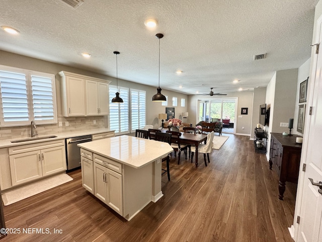 kitchen featuring sink, white cabinetry, a center island, decorative light fixtures, and stainless steel dishwasher