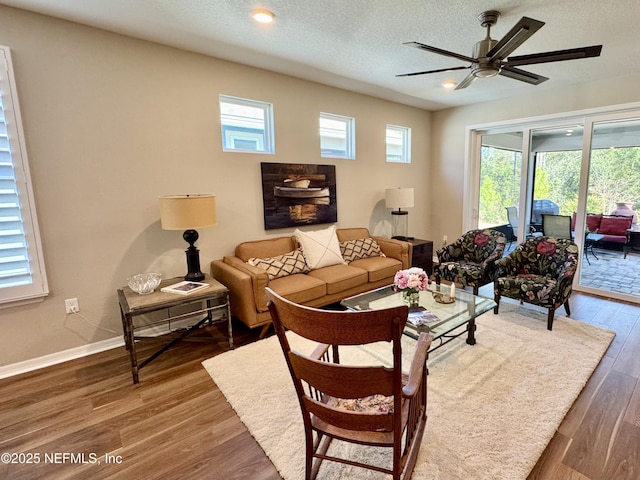 living room featuring ceiling fan, plenty of natural light, dark wood-type flooring, and a textured ceiling