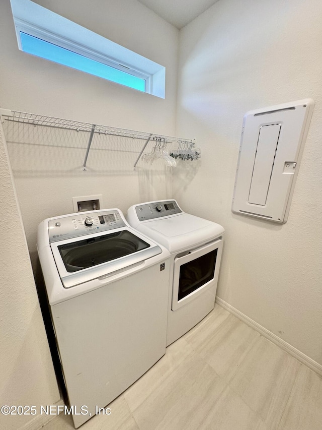 laundry room featuring separate washer and dryer, light hardwood / wood-style floors, and electric panel