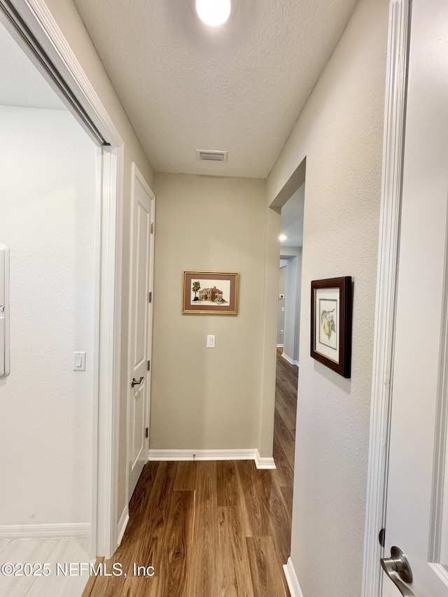 hall featuring hardwood / wood-style floors and a textured ceiling