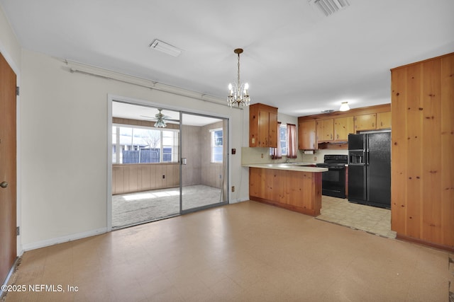 kitchen with pendant lighting, kitchen peninsula, a chandelier, and black appliances