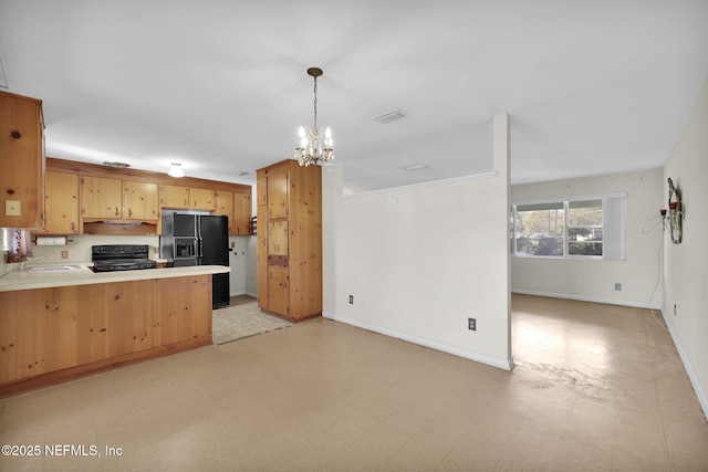 kitchen with pendant lighting, kitchen peninsula, sink, black appliances, and an inviting chandelier