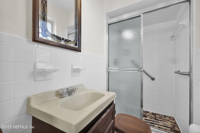 bathroom featuring vanity, toilet, tile walls, and walk in shower