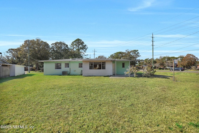 rear view of house with cooling unit and a lawn