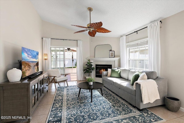 living room with lofted ceiling, light tile patterned floors, a tile fireplace, and a healthy amount of sunlight