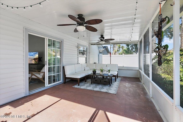 sunroom featuring plenty of natural light, rail lighting, and ceiling fan