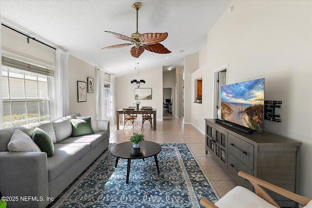 living room featuring ceiling fan, lofted ceiling, light tile patterned floors, and a textured ceiling