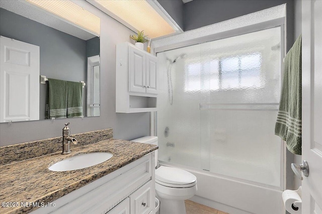 full bathroom featuring vanity, toilet, tile patterned flooring, and combined bath / shower with glass door