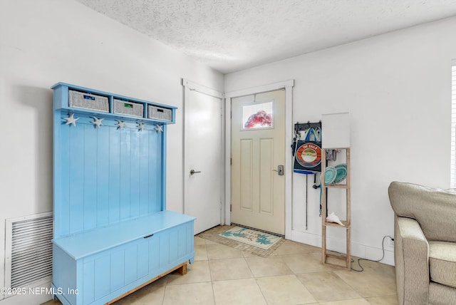 mudroom with a textured ceiling, light tile patterned floors, and visible vents