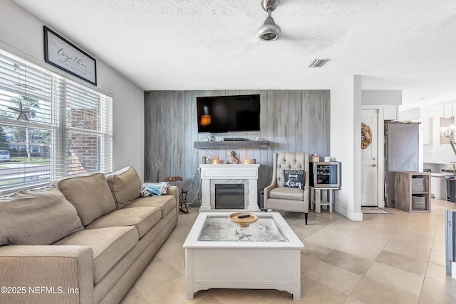 living room with an accent wall, visible vents, a textured ceiling, and a premium fireplace