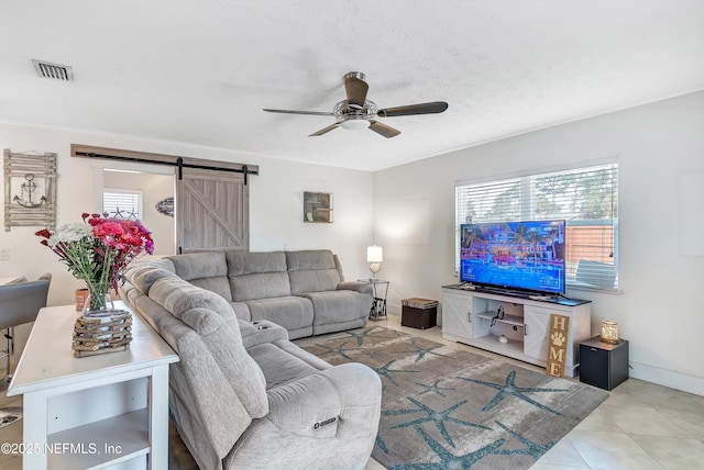 living room with a ceiling fan, a healthy amount of sunlight, visible vents, and a barn door