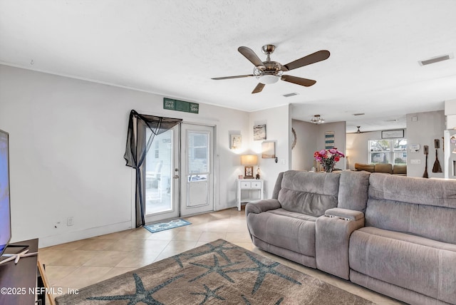 living area featuring light tile patterned floors, a textured ceiling, visible vents, and a ceiling fan