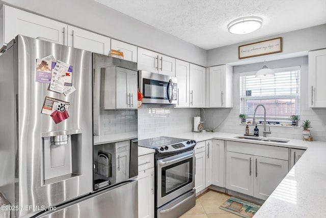 kitchen with light tile patterned floors, stainless steel appliances, backsplash, white cabinets, and a sink