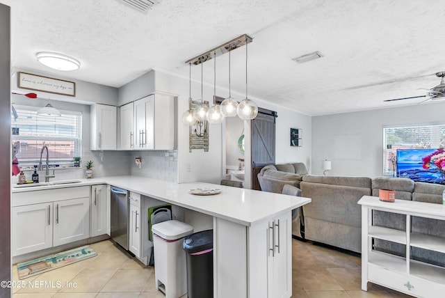 kitchen with light countertops, a barn door, open floor plan, a sink, and a peninsula