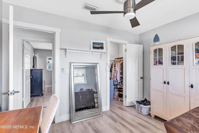 bedroom with ceiling fan, light wood-style flooring, visible vents, baseboards, and a closet