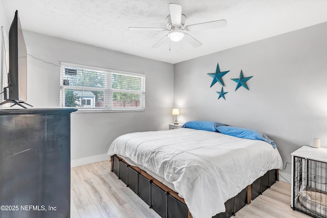 bedroom with baseboards, a textured ceiling, a ceiling fan, and light wood-style floors