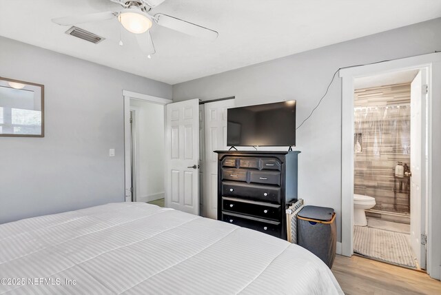 bedroom featuring light wood-style floors, visible vents, ceiling fan, and ensuite bath