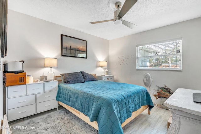 bedroom with light wood-style floors, a ceiling fan, and a textured ceiling