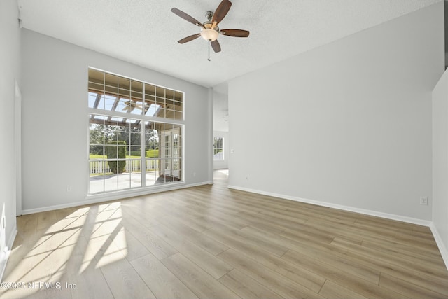 empty room with a textured ceiling, light hardwood / wood-style floors, and ceiling fan