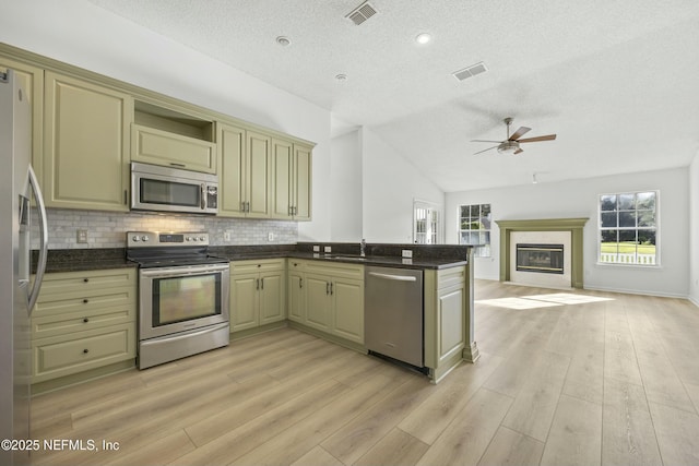 kitchen with light hardwood / wood-style flooring, stainless steel appliances, lofted ceiling, decorative backsplash, and kitchen peninsula