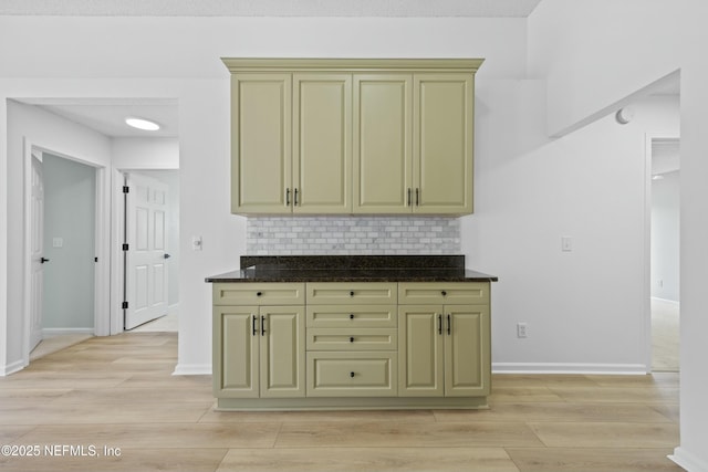 kitchen featuring light wood-type flooring, dark stone countertops, and decorative backsplash