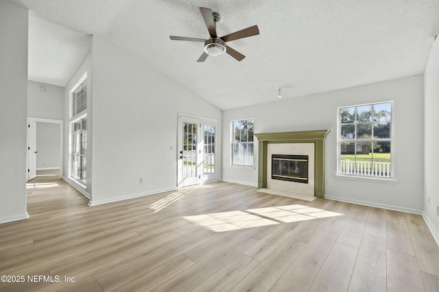 unfurnished living room featuring a textured ceiling, ceiling fan, a high end fireplace, and light hardwood / wood-style floors