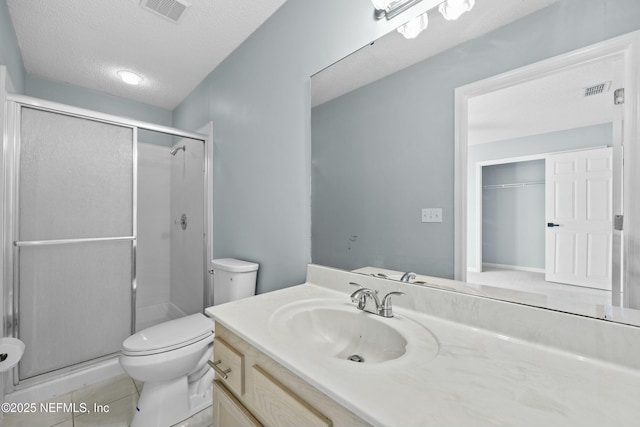 bathroom with vanity, an enclosed shower, a textured ceiling, tile patterned flooring, and toilet