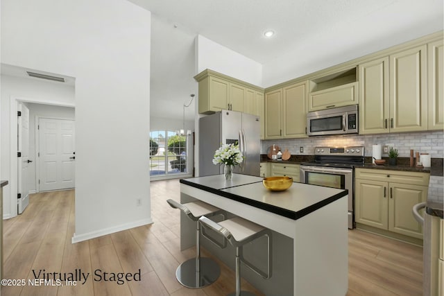 kitchen with light hardwood / wood-style floors, stainless steel appliances, and decorative backsplash