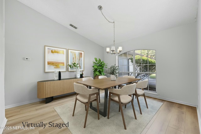 dining area featuring light wood-type flooring, lofted ceiling, and a chandelier