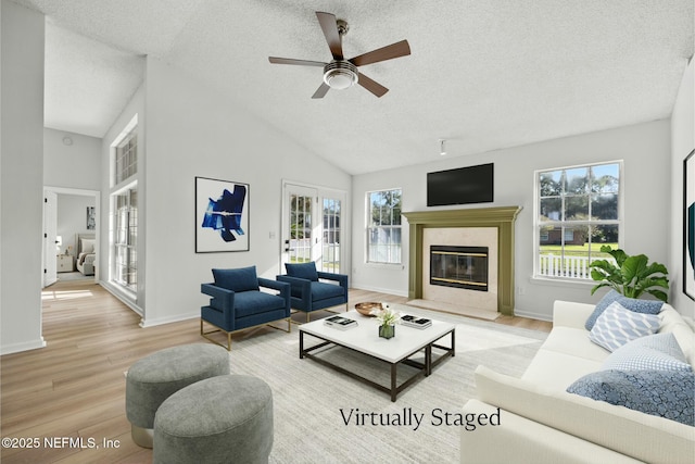 living room with light hardwood / wood-style flooring, plenty of natural light, a high end fireplace, and a textured ceiling