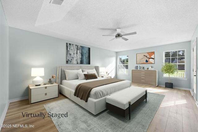 bedroom featuring hardwood / wood-style floors, ceiling fan, and a textured ceiling