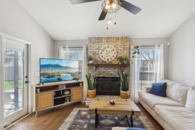 living room featuring dark wood-type flooring, a fireplace, vaulted ceiling, and a textured ceiling