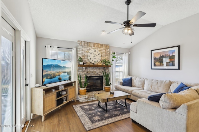 living room featuring lofted ceiling, dark wood-type flooring, a wealth of natural light, and a fireplace