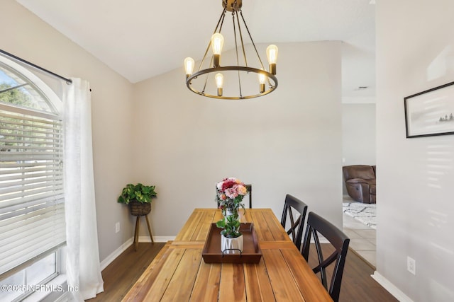 dining space with vaulted ceiling, wood-type flooring, and a chandelier