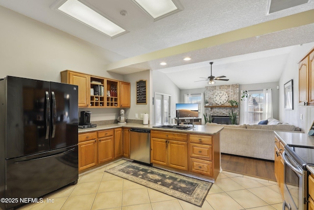 kitchen featuring light tile patterned floors, ceiling fan, appliances with stainless steel finishes, a fireplace, and vaulted ceiling