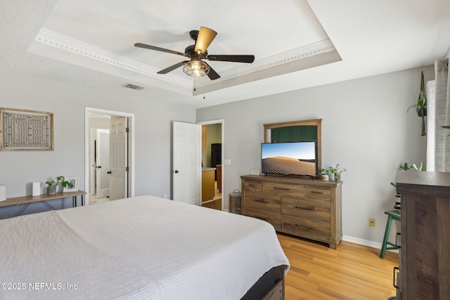 bedroom with a tray ceiling, wood-type flooring, and ceiling fan