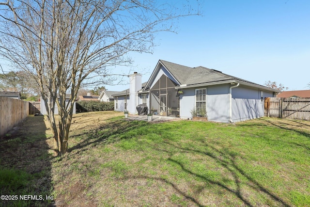 back of property with a lawn, a sunroom, and a patio