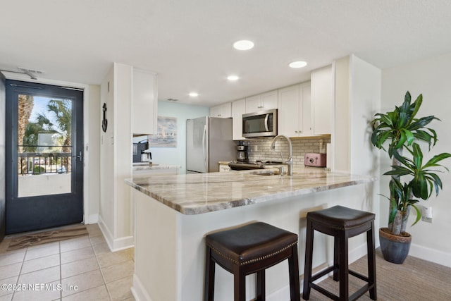 kitchen featuring appliances with stainless steel finishes, kitchen peninsula, sink, and white cabinets