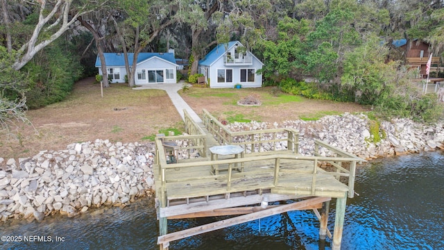 view of dock with a water view and a lawn