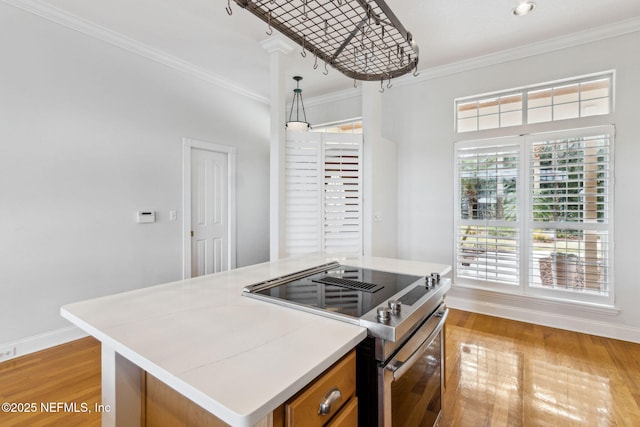 kitchen featuring crown molding, stainless steel electric range oven, a center island, light wood-type flooring, and pendant lighting