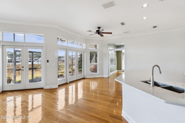 interior space with sink, ornamental molding, light hardwood / wood-style floors, and french doors