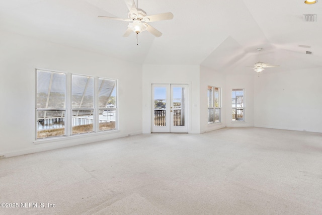 unfurnished living room featuring vaulted ceiling, light colored carpet, french doors, and ceiling fan