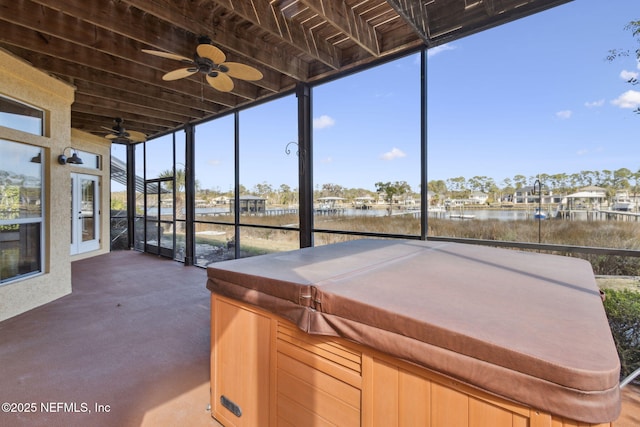 unfurnished sunroom with a water view and ceiling fan