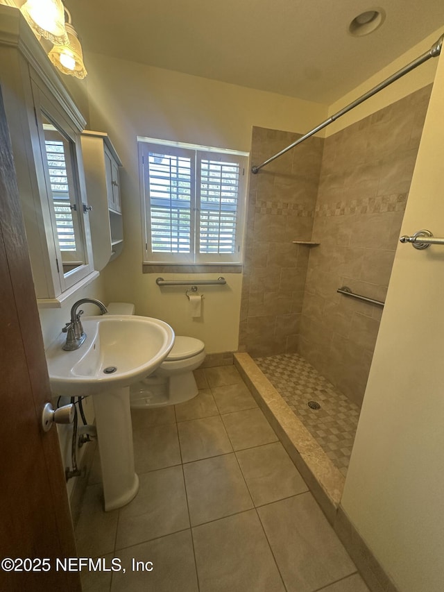 bathroom with tile patterned flooring, plenty of natural light, toilet, and tiled shower