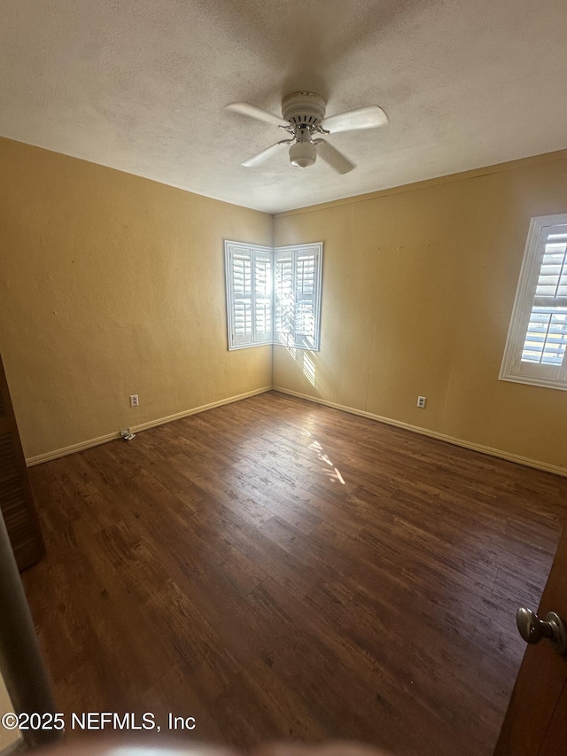 unfurnished room featuring dark hardwood / wood-style floors, a textured ceiling, and a wealth of natural light