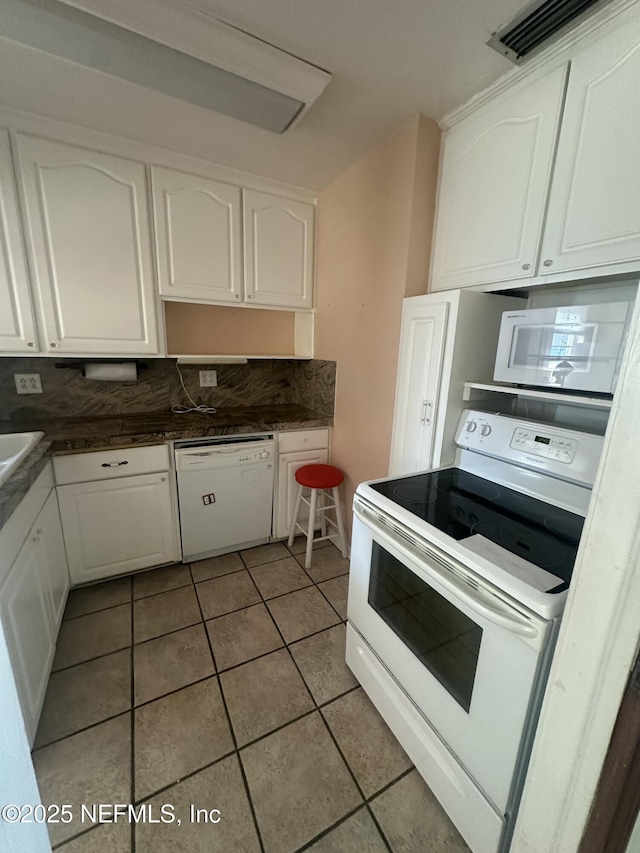 kitchen with white cabinetry, sink, light tile patterned floors, and white appliances