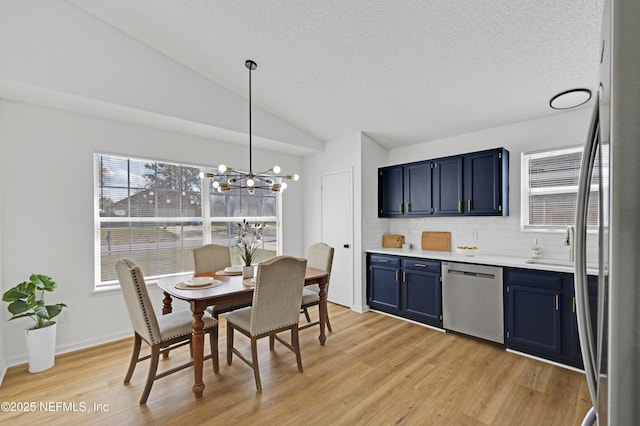 dining area with lofted ceiling, sink, light hardwood / wood-style floors, a textured ceiling, and a chandelier