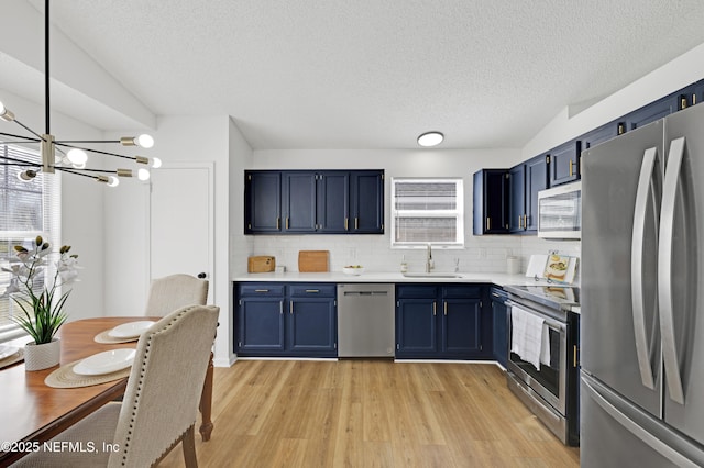 kitchen with blue cabinets, appliances with stainless steel finishes, sink, and light hardwood / wood-style floors